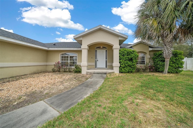 view of front of property featuring stucco siding, a front lawn, and fence