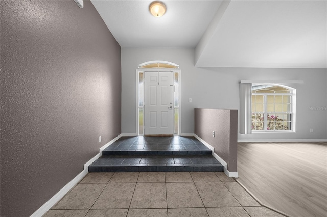 entryway with baseboards, tile patterned flooring, and a textured wall