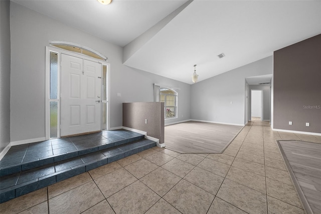 tiled entrance foyer with visible vents, baseboards, and lofted ceiling
