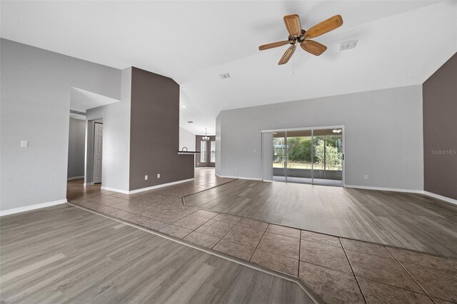 unfurnished living room featuring tile patterned flooring, visible vents, baseboards, and high vaulted ceiling