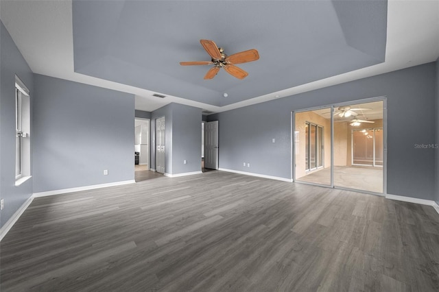 unfurnished bedroom featuring visible vents, a raised ceiling, wood finished floors, connected bathroom, and baseboards
