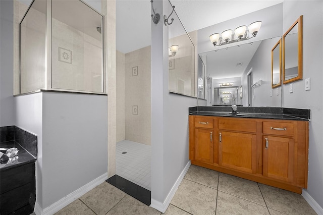 bathroom featuring tile patterned flooring, vanity, baseboards, and walk in shower