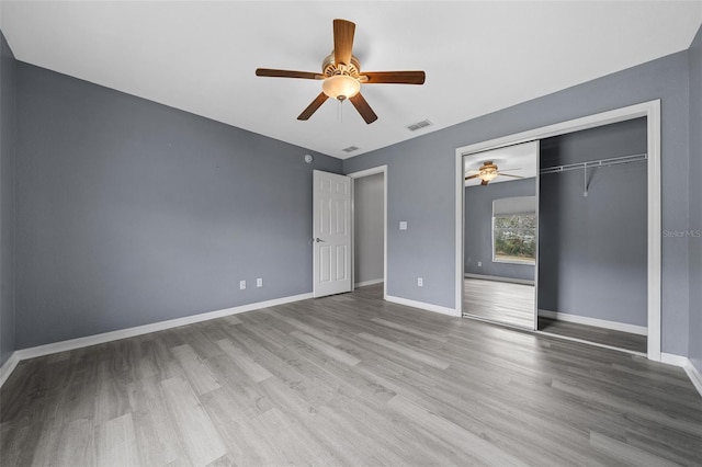 unfurnished bedroom with a closet, visible vents, baseboards, and wood finished floors