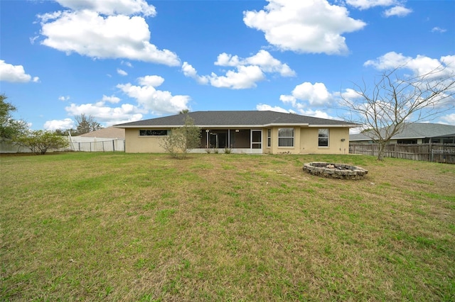 rear view of house featuring an outdoor fire pit, a yard, a fenced backyard, a sunroom, and stucco siding