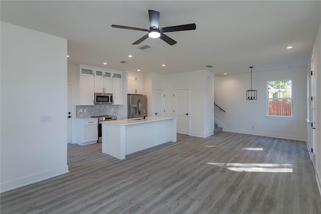 kitchen featuring stainless steel appliances, white cabinets, visible vents, and backsplash