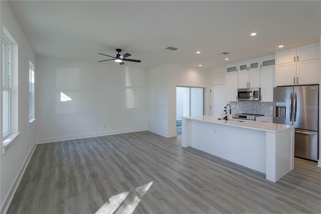 kitchen featuring tasteful backsplash, visible vents, stainless steel appliances, light countertops, and a sink