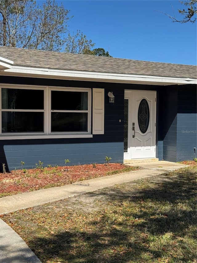 exterior space featuring roof with shingles and concrete block siding