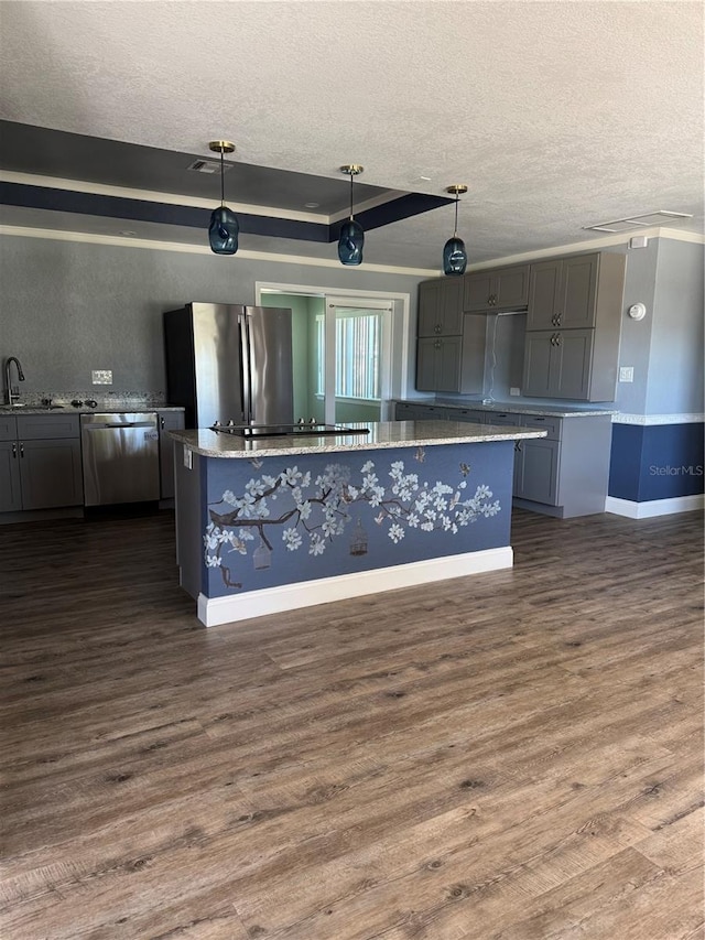 kitchen featuring dark wood-style floors, appliances with stainless steel finishes, a sink, and a kitchen island