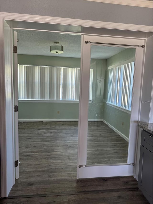 empty room featuring dark wood finished floors, a textured ceiling, and baseboards