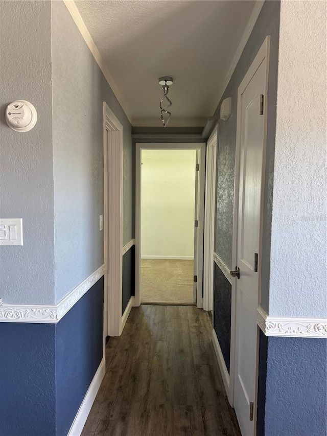 corridor with a textured wall, a textured ceiling, baseboards, and wood finished floors