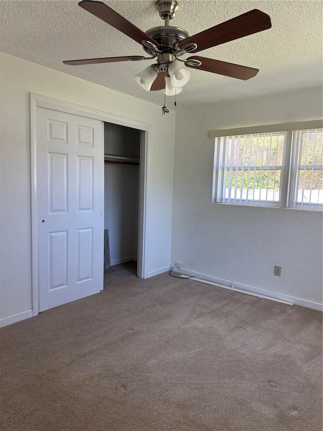 unfurnished bedroom featuring carpet, a closet, ceiling fan, a textured ceiling, and baseboards