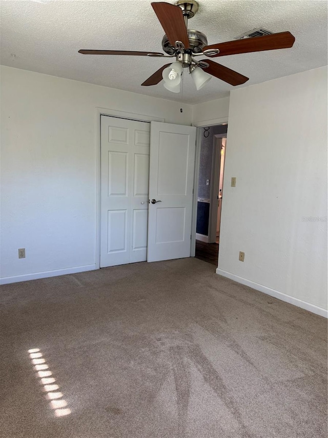 unfurnished bedroom featuring carpet floors, a closet, a textured ceiling, and baseboards