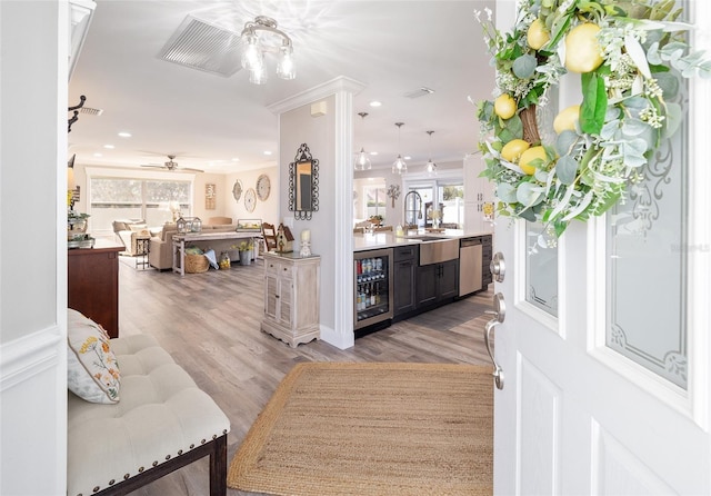 bar with wine cooler, crown molding, light wood finished floors, a sink, and dishwasher