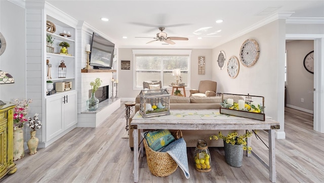 living area featuring a fireplace, recessed lighting, ornamental molding, light wood-type flooring, and baseboards