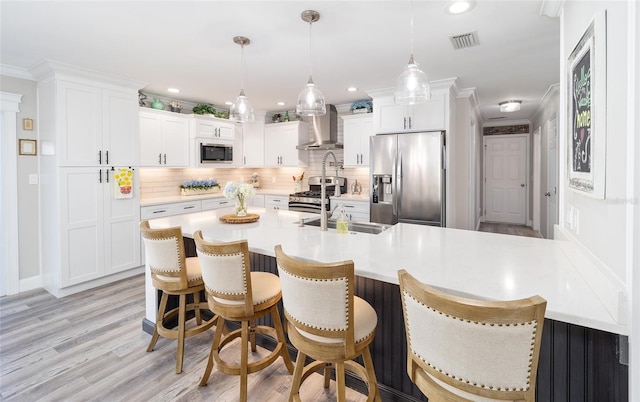 kitchen featuring light countertops, visible vents, appliances with stainless steel finishes, white cabinetry, and wall chimney range hood