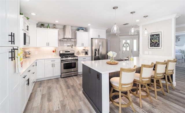 kitchen featuring stainless steel appliances, ornamental molding, backsplash, wall chimney exhaust hood, and a kitchen bar