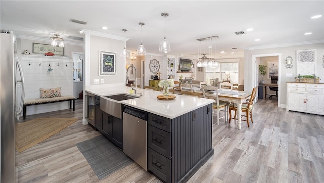 kitchen with visible vents, appliances with stainless steel finishes, light countertops, crown molding, and a sink