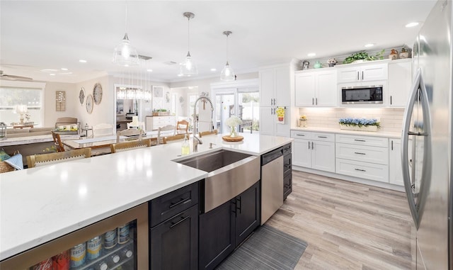 kitchen featuring stainless steel appliances, a sink, white cabinetry, light countertops, and ornamental molding