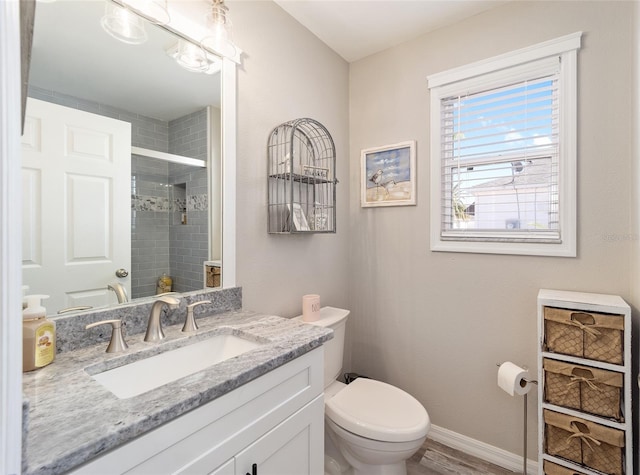 bathroom with baseboards, a shower stall, toilet, and vanity