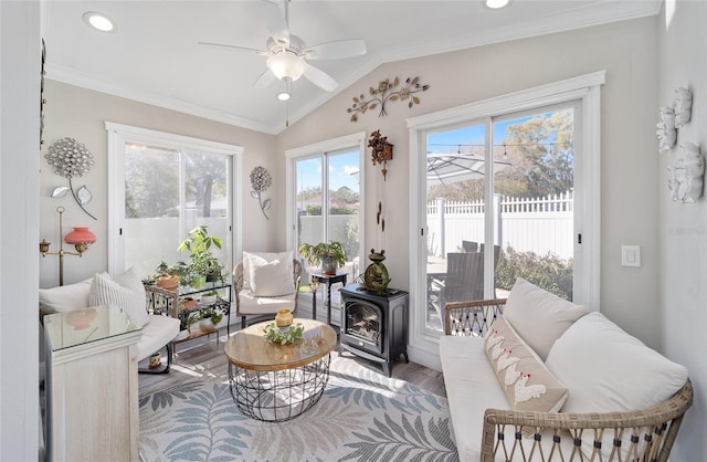 sunroom / solarium with lofted ceiling, ceiling fan, and a wood stove