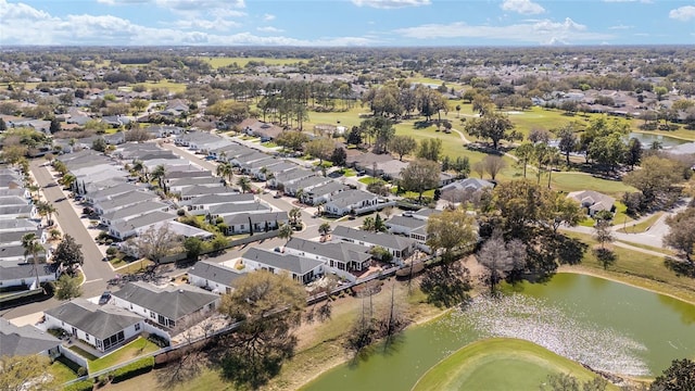 drone / aerial view featuring golf course view, a water view, and a residential view