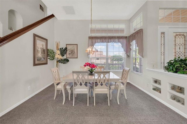 carpeted dining room featuring visible vents, built in shelves, and baseboards