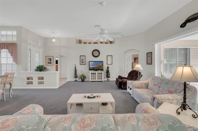 carpeted living room with arched walkways, visible vents, ceiling fan, and baseboards