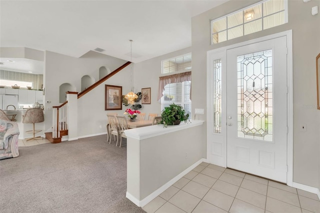 foyer entrance with light carpet, visible vents, baseboards, and stairs