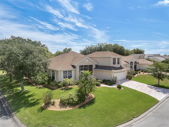 view of front facade with a garage, a front lawn, and decorative driveway