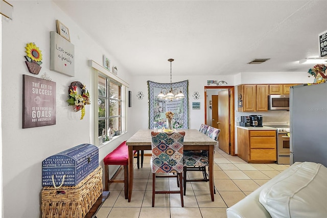 dining room with light tile patterned floors, visible vents, and an inviting chandelier