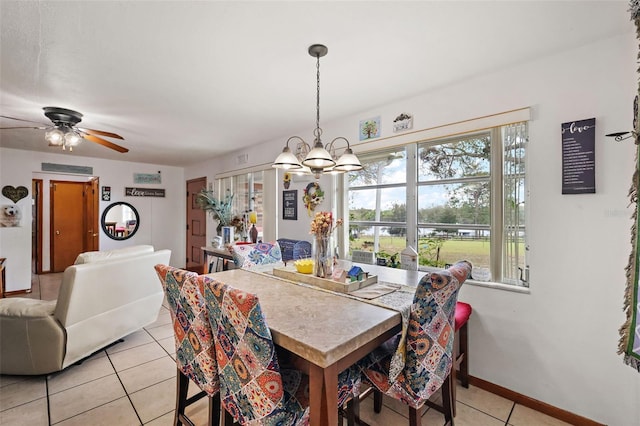 dining space featuring light tile patterned flooring, ceiling fan with notable chandelier, and baseboards