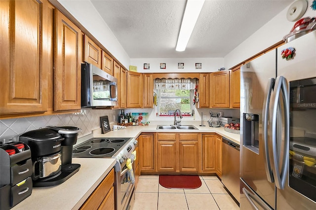 kitchen featuring a sink, appliances with stainless steel finishes, brown cabinetry, and light countertops