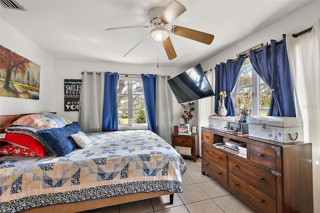 bedroom with multiple windows, light tile patterned flooring, visible vents, and ceiling fan