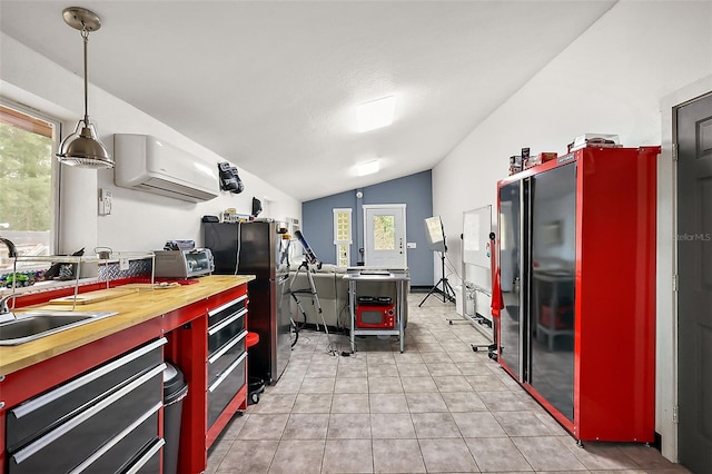 kitchen with a wall unit AC, freestanding refrigerator, a sink, vaulted ceiling, and butcher block counters