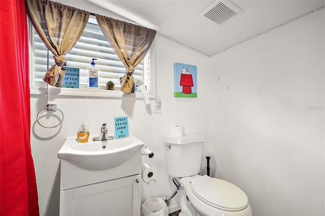 half bath featuring vanity, toilet, and visible vents