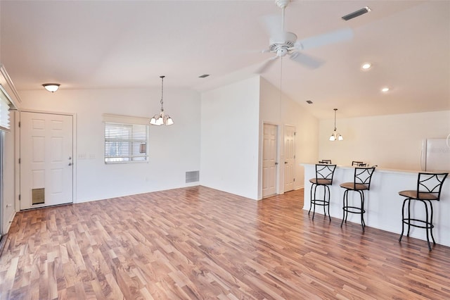 living room featuring light wood-style floors, visible vents, vaulted ceiling, and ceiling fan