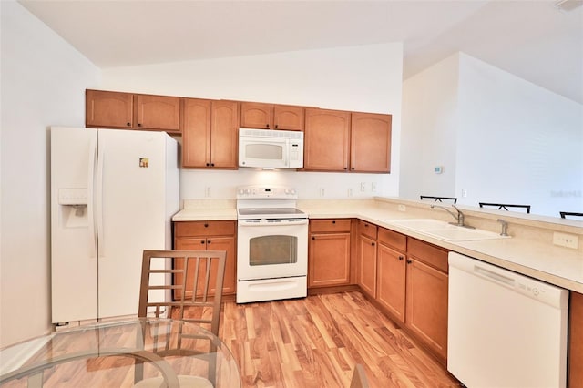 kitchen with vaulted ceiling, white appliances, light wood-type flooring, and a sink