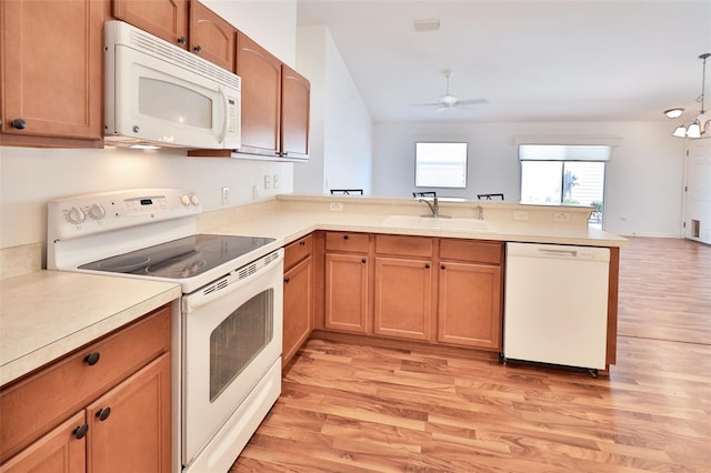 kitchen with white appliances, light wood-style flooring, a peninsula, light countertops, and a sink