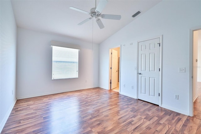 unfurnished bedroom with lofted ceiling, wood finished floors, a ceiling fan, visible vents, and baseboards