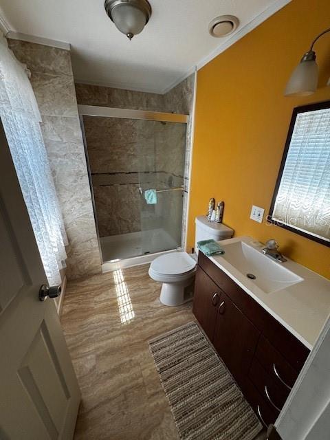 full bath with a stall shower, toilet, and vanity