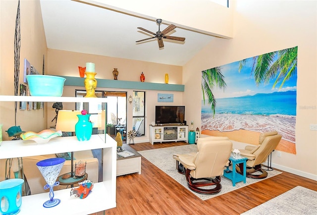 living room with a ceiling fan, vaulted ceiling, wood finished floors, and baseboards