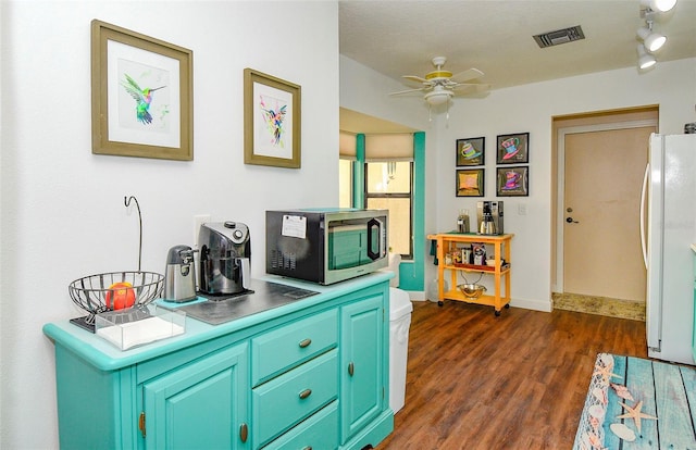 kitchen featuring visible vents, dark wood-type flooring, a ceiling fan, freestanding refrigerator, and baseboards