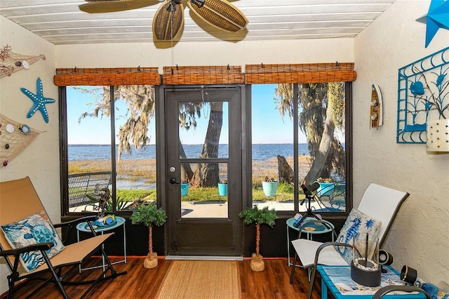 sunroom / solarium with plenty of natural light, ceiling fan, and a water view