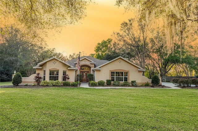 view of front of home featuring stucco siding, a front yard, and french doors