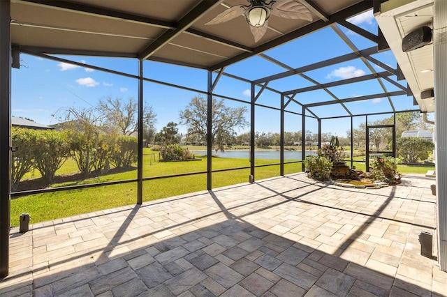 unfurnished sunroom with a ceiling fan and a water view