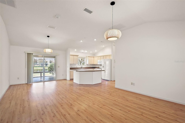 kitchen featuring open floor plan, white fridge with ice dispenser, dark countertops, and lofted ceiling