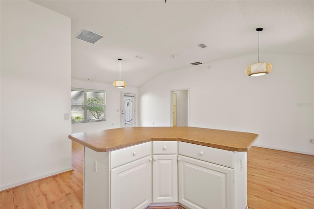 kitchen with lofted ceiling, light wood finished floors, white cabinetry, and visible vents