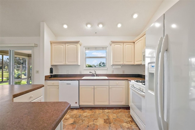 kitchen with dark countertops, white appliances, a sink, and recessed lighting