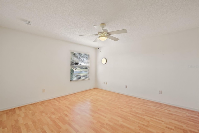 empty room with a textured ceiling, wood finished floors, and a ceiling fan