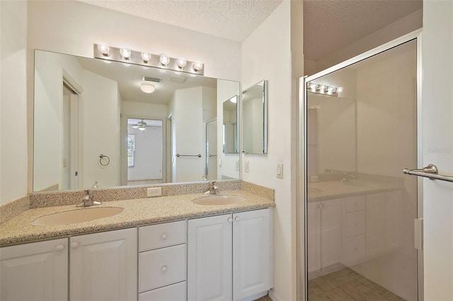 full bath featuring a textured ceiling, a stall shower, and a sink